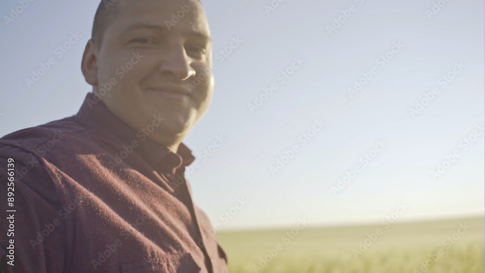Close up portrait of smiling man standing in green wheat field on sunset and looking at the camera - slow motion Close up portrait of smiling man standing in green wheat field on sunset and looking at the camera - slow motion