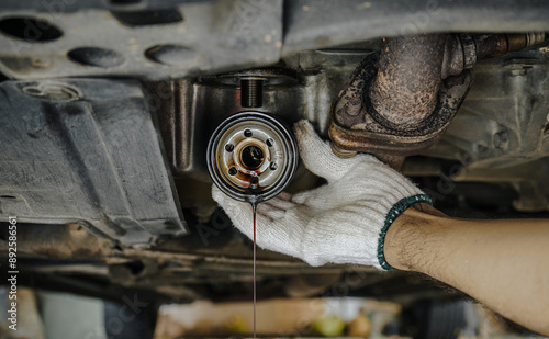 Close-up of auto mechanic's hands removing the underside oil filter of a car. Dirty used oil filter in man's hand at service station, car maintenance concept