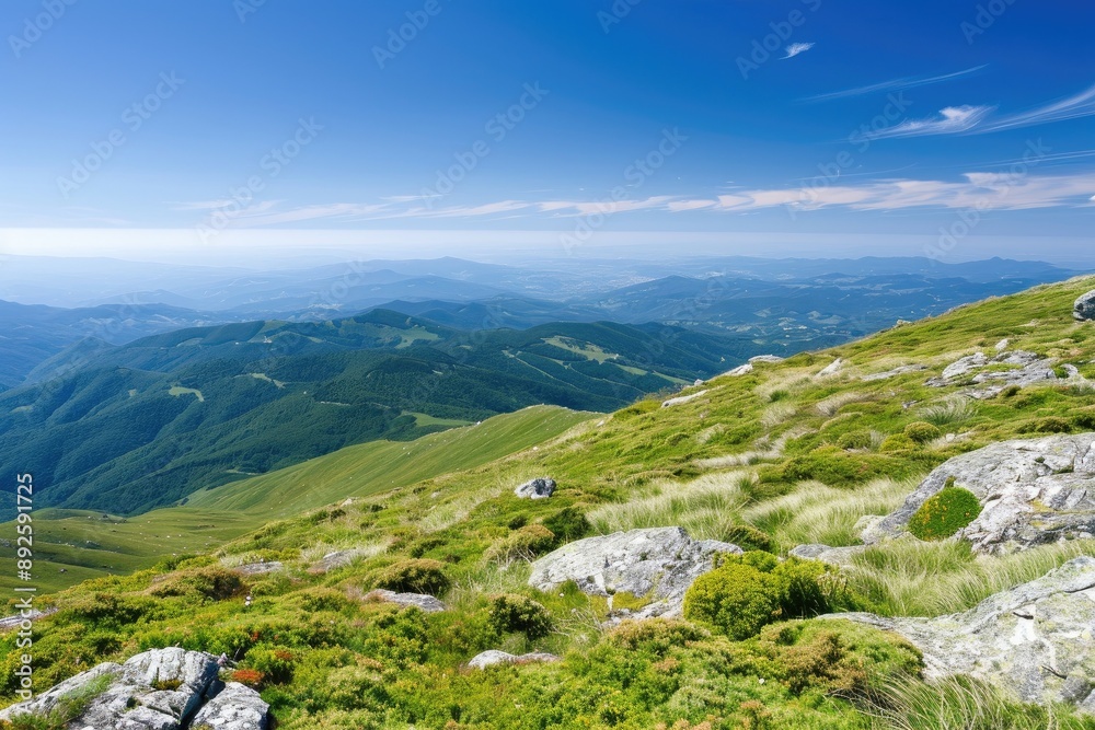 Fototapeta premium Stunning mountain landscape with rolling green hills and a clear blue sky, offering a serene and picturesque view of nature at its finest.