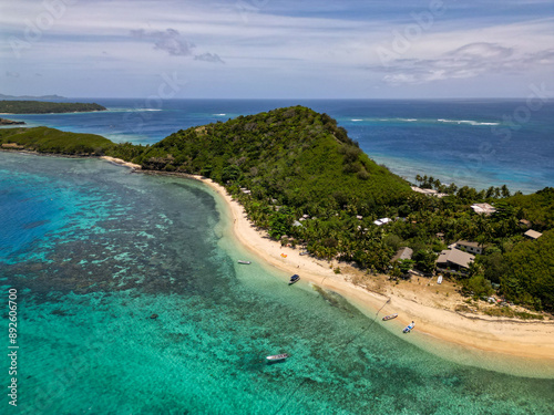 Aerial view of tropical island beach with shallow turquoise water and corals reefs seen from above. Boats and resort perched on Mantaray Island in Fiji's famous touristic Yasawa region.  photo