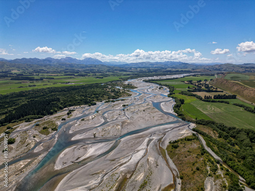 Aerial view of braided river formed from glacial melt and sediment. Shallow channels of water interweave into the mountains on the horizon photo