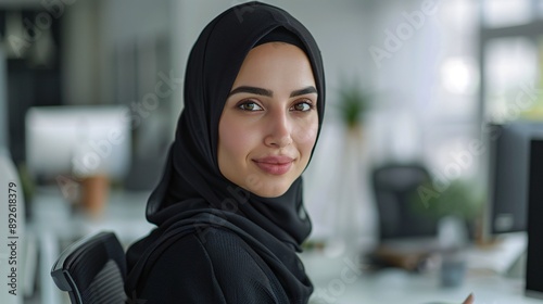 Professional hijab woman, clean minimal office workspace, looking at computer, white setting, over-the-shoulder shot, professional photography.