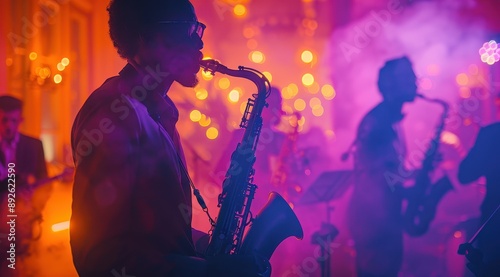 A group of musicians playing saxophone and trumpets in silhouette against the backdrop of purple lights on stage