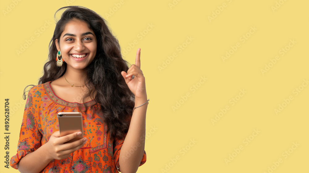Smiling Indian girl Pointing her finger to announce a promotion from her mobile phone Empty space for full words, colored background. Advertising. Smiling Indian girl Pointing her finger to announce a promotion from her mobile phone Empty space for full words, colored background. Advertising.
