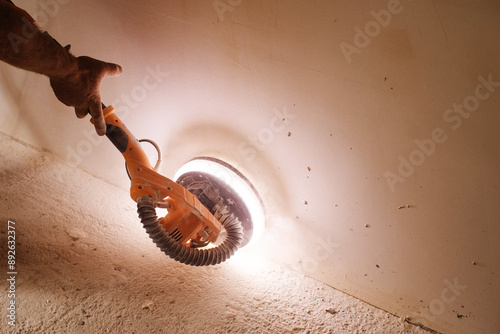 Konstfotografi A plasterer's hand and a grinder for plaster and putty at work with a backlight