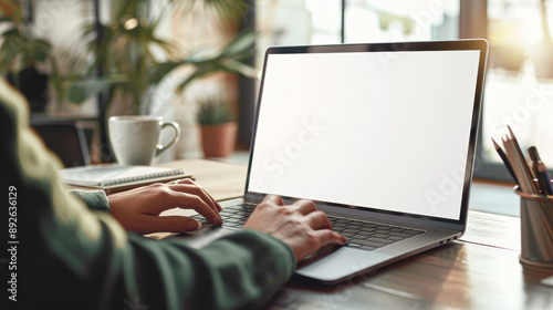Close up of a woman's hands typing on a laptop with a blank white screen as a pro mockup in an office