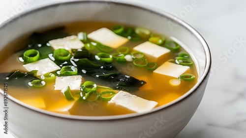 A close-up of a bowl of miso soup with tofu, seaweed, and green onions, in a minimalist kitchen, high-resolution photo, realistic photo, cinematography, hyper realistic
