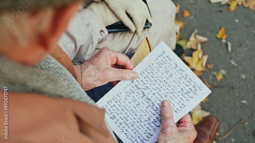 Elderly person opening handwritten letter in park photo