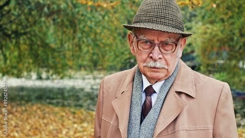 Portrait of elderly sad and inelastic man in sunny park photo