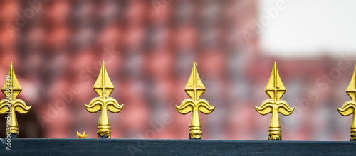 Fotografi A row of gold spikes are on a black fence