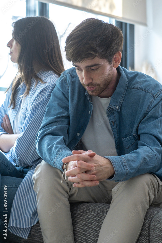 Sad man and girlfriend sitting on the sofa after bad discussion about financial family problem. Young adult couple ignoring themselves. Relationship difficulties with millennial people in indoor Sad man and girlfriend sitting on the sofa after bad discussion about financial family problem. Young adult couple ignoring themselves. Relationship difficulties with millennial people in indoor