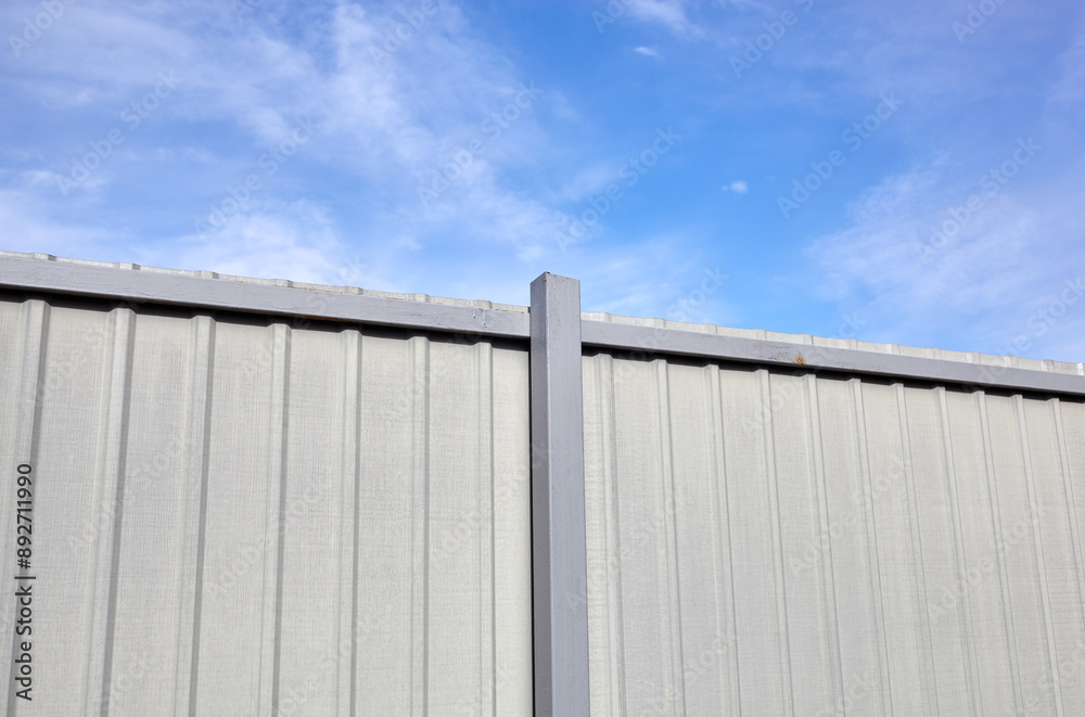 Corrugated steel fence against blue sky. Corrugated metal texture surface or galvanize steel Corrugated steel fence against blue sky. Corrugated metal texture surface or galvanize steel
