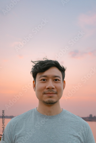 Portrait of asian man standing with smooth colorful sunset sky.