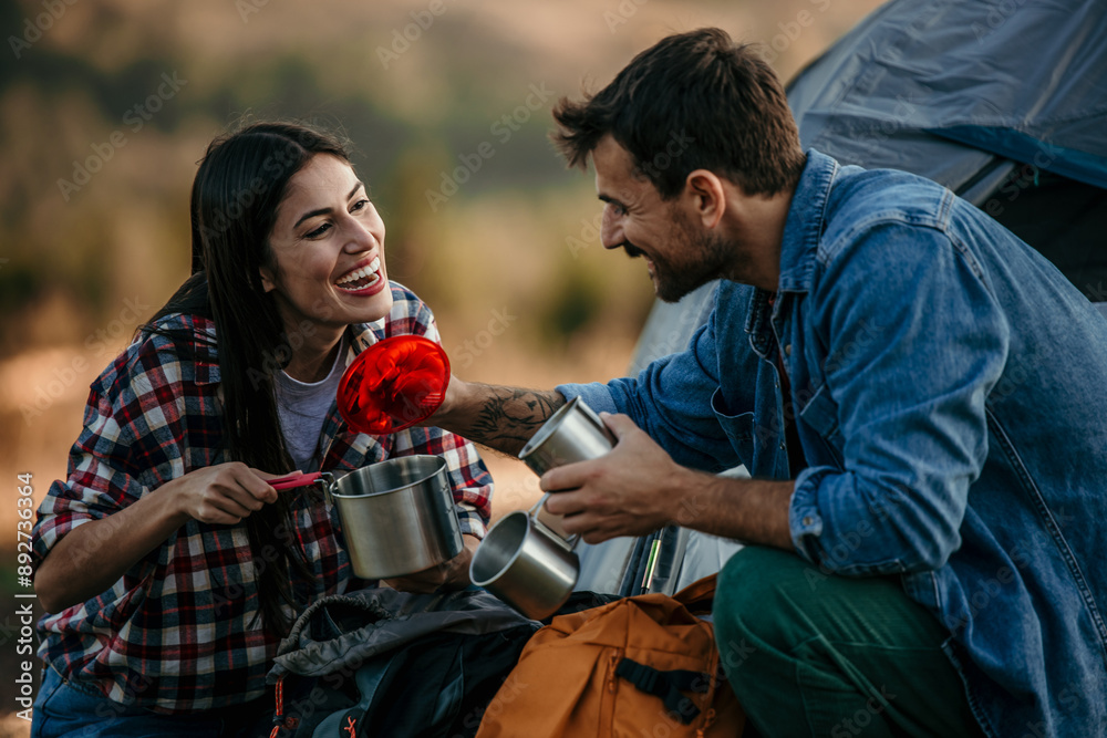 An adventurous young couple at their campsite and drinking coffee An adventurous young couple at their campsite and drinking coffee