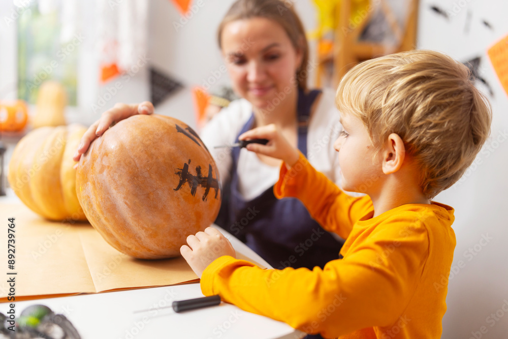 Fototapeta premium Child painting face on pumpkin for Halloween