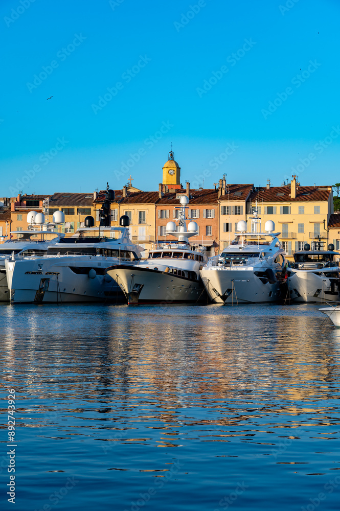 Obraz premium Old port of Saint-Tropez famous touristic village on French Riviera, summer vacation with large yacht boats and colorful houses