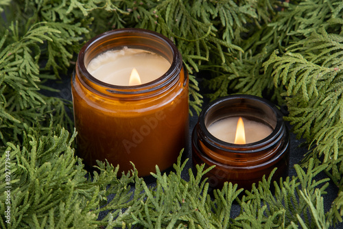 Soy candle in a glass jar. Green thuja branches. Scented candles photo