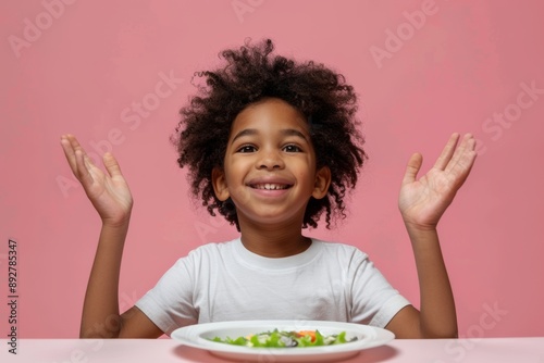 Playful young boy yellow shirt holds palms enthusiastically. Smiling curly-haired child table ready to enjoy delicious meal. Interactive charm of child's anticipation framed cozy setting. photo