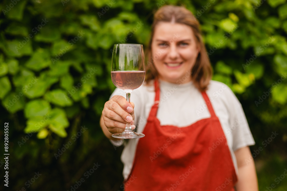30s Woman in apron tasting red wine in vineyard. Portrait of pretty young woman holding glass of wine. Happy vintner drinks wine after successful grape harvesting, Natural wine industry. Harvest time 30s Woman in apron tasting red wine in vineyard. Portrait of pretty young woman holding glass of wine. Happy vintner drinks wine after successful grape harvesting, Natural wine industry. Harvest time