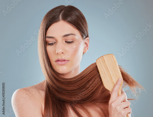 Studio, woman and brush for hair care with grooming, detangle and smooth texture for styling. Girl model, tool and maintenance for knot, growth and wellness treatment for cosmetics in gray background photo