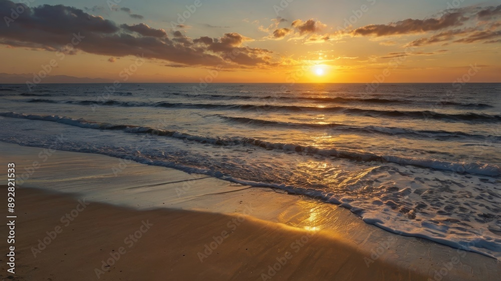 Obraz premium Golden Sunset Over Rippling Ocean Waves on a Sandy Beach