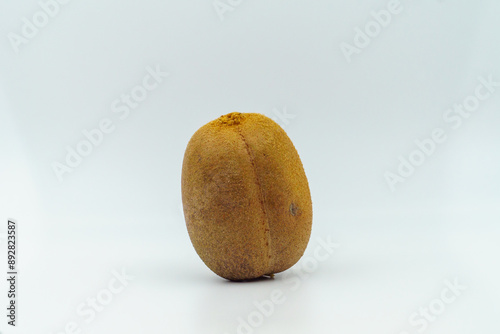 Whole kiwi fruit standing upright on a plain white background, showcasing its brown fuzzy skin. Concept of fresh produce photo