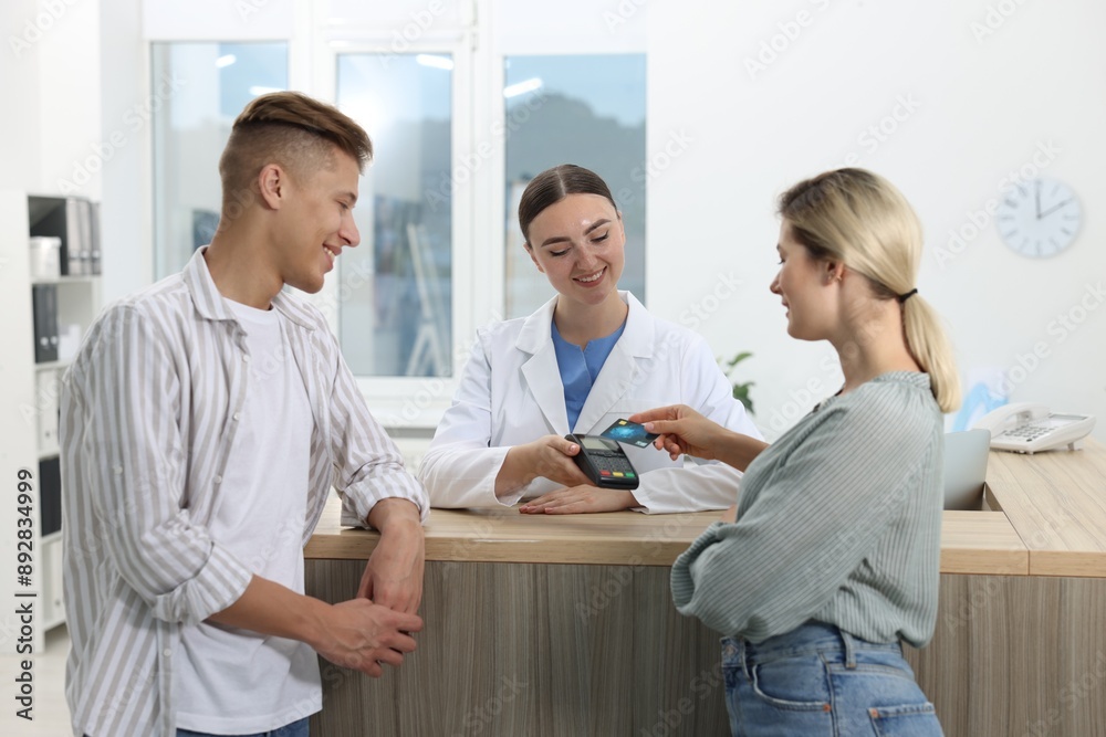 Fototapeta premium Receptionist taking payment from client via terminal at hospital