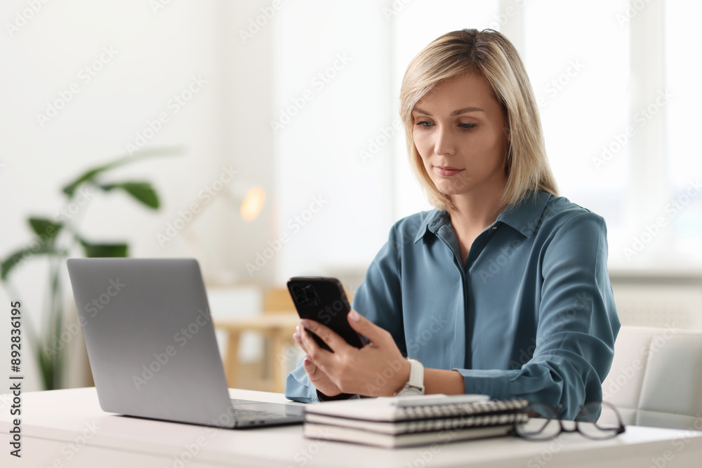 Woman using mobile phone at white table indoors Woman using mobile phone at white table indoors