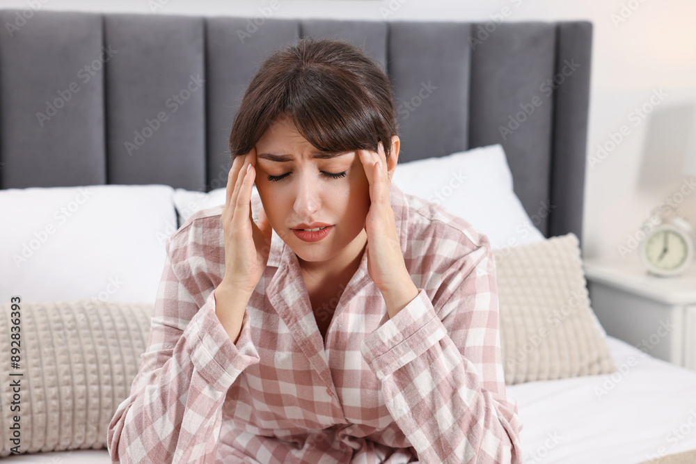 Upset woman suffering from headache on bed at home Upset woman suffering from headache on bed at home