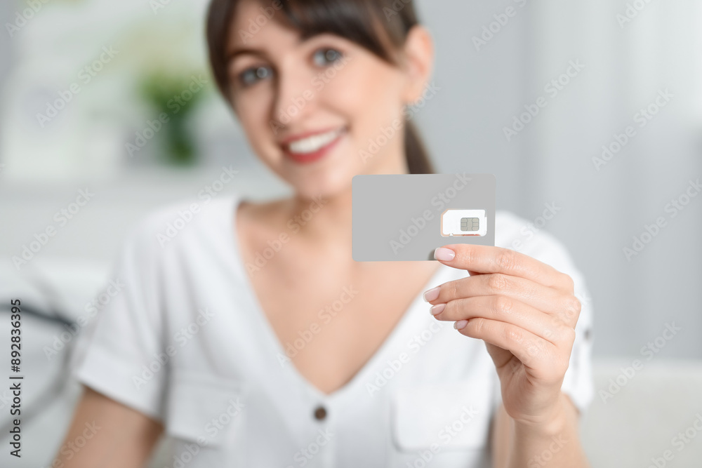 Woman holding SIM card indoors, selective focus Woman holding SIM card indoors, selective focus