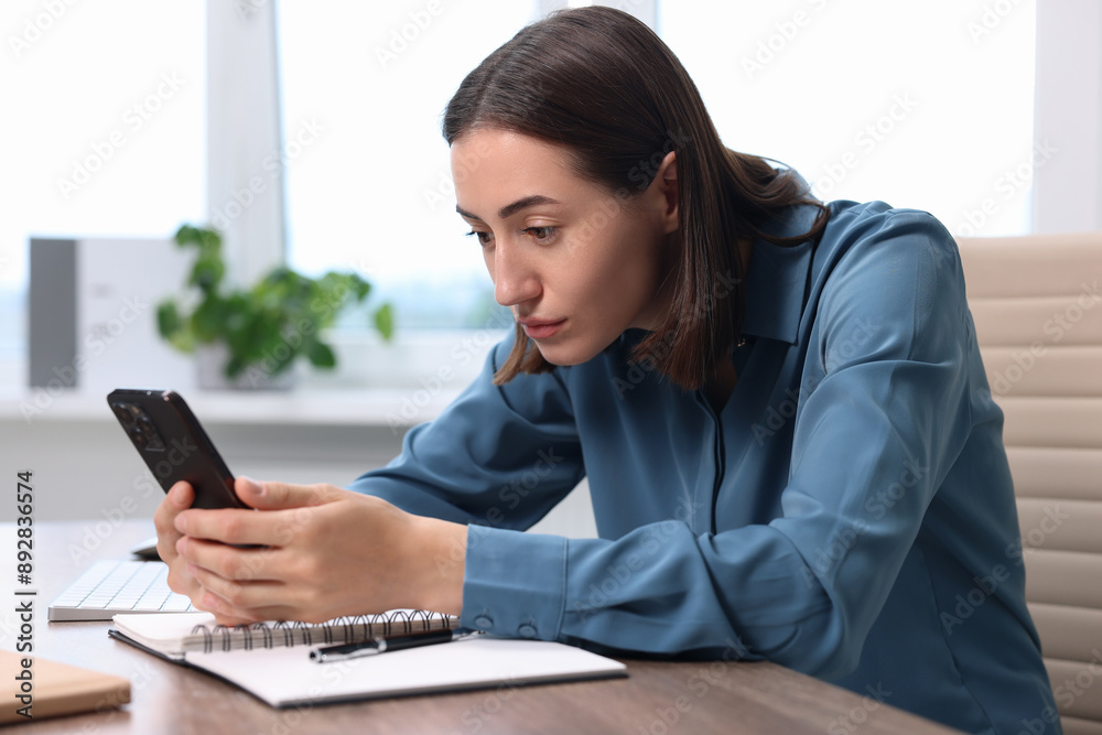 Woman with poor posture using smartphone in office Woman with poor posture using smartphone in office
