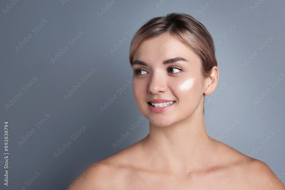 Beautiful woman with cream on her face against gray background Beautiful woman with cream on her face against gray background