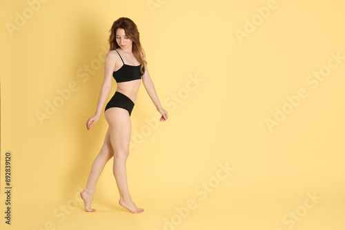 Woman with slim body posing on yellow background, space for text