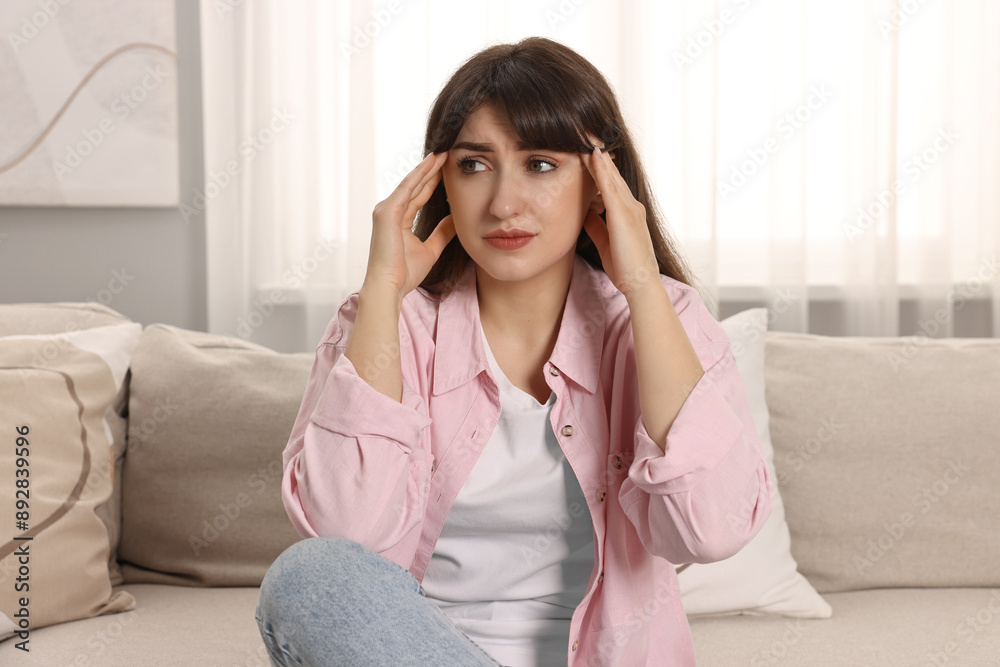 Upset woman suffering from headache on sofa at home Upset woman suffering from headache on sofa at home