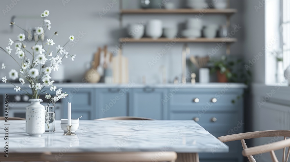 Clean, empty marble dining table in a Scandinavian kitchen with blue drawers on wood furniture. Modern monochrome interior with tableware and flower vases. Clean, empty marble dining table in a Scandinavian kitchen with blue drawers on wood furniture. Modern monochrome interior with tableware and flower vases.