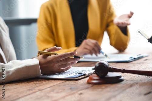A professional consultation scene featuring hands discussing documents and a gavel, symbolizing legal proceedings and decision-making.