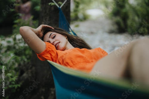 Canvas-taulu Smiling young woman enjoying a peaceful moment in a hammock outdoors
