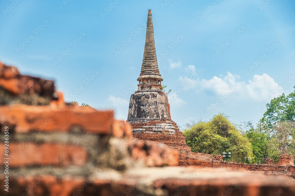 Fototapeta premium Historical Buddhist stupa on archaelogical site in Ayutthaya historical park Wat Mahathat temple, Thailand. Ancient red brick stupa in Asia. Ancient architectural and cultural heritage