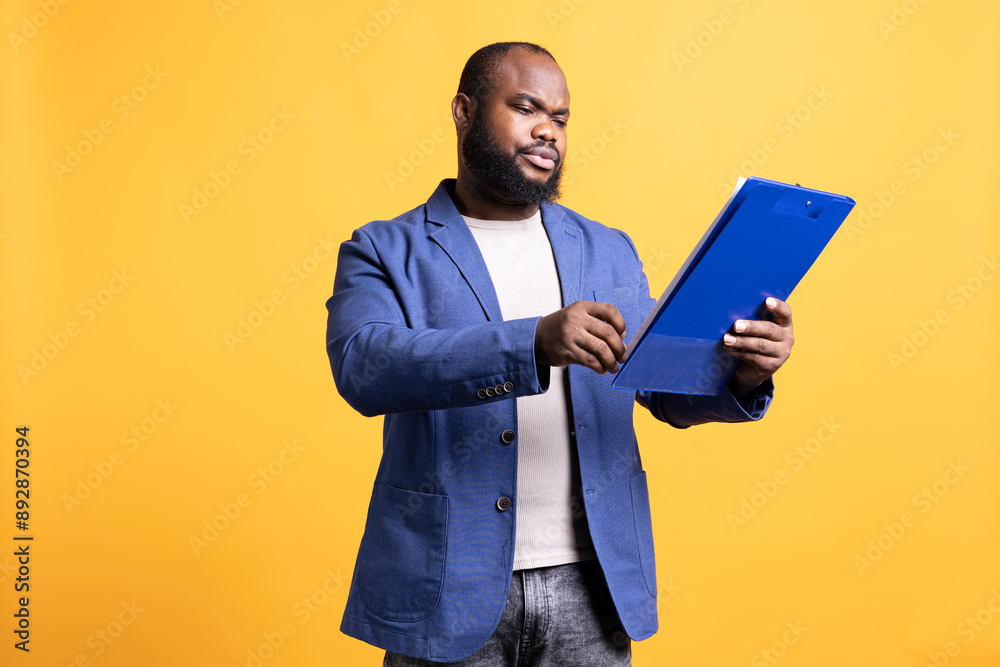 Man working accounting job browsing though financial report pages, studio background. Worker reading paperwork containing economic graphs and figures, solving bookkeeping tasks Man working accounting job browsing though financial report pages, studio background. Worker reading paperwork containing economic graphs and figures, solving bookkeeping tasks
