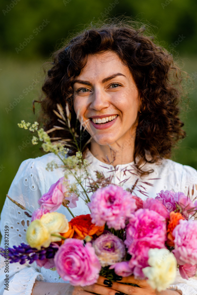 Summer portrait of young beautiful attractive woman in a meadow in a white lace dress holding bright bouquet of ranunculi flowers. Summertime, sunset, golden hour. Freedom and happiness Summer portrait of young beautiful attractive woman in a meadow in a white lace dress holding bright bouquet of ranunculi flowers. Summertime, sunset, golden hour. Freedom and happiness