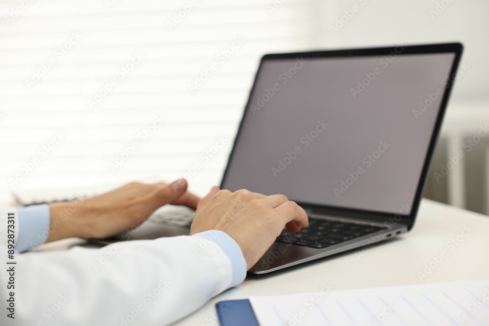 Doctor using laptop at white table in hospital, closeup Doctor using laptop at white table in hospital, closeup