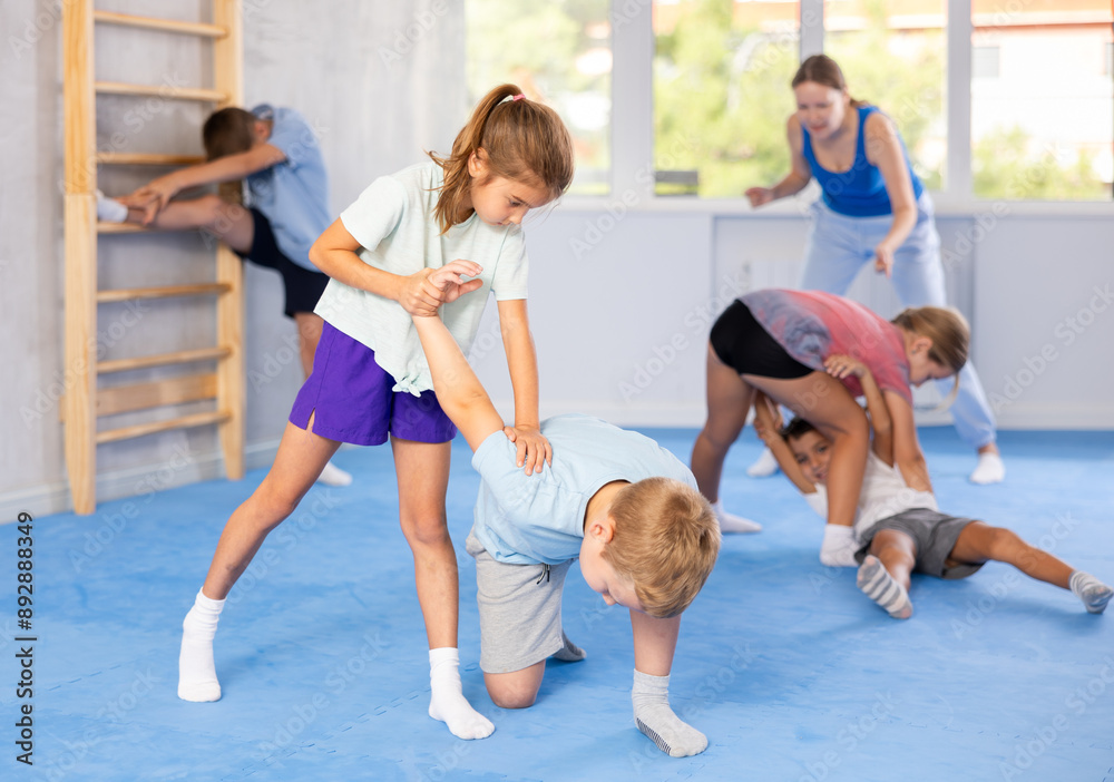 Obraz premium Kids in sportswear exercising self-protection techniques in pair during class at gym