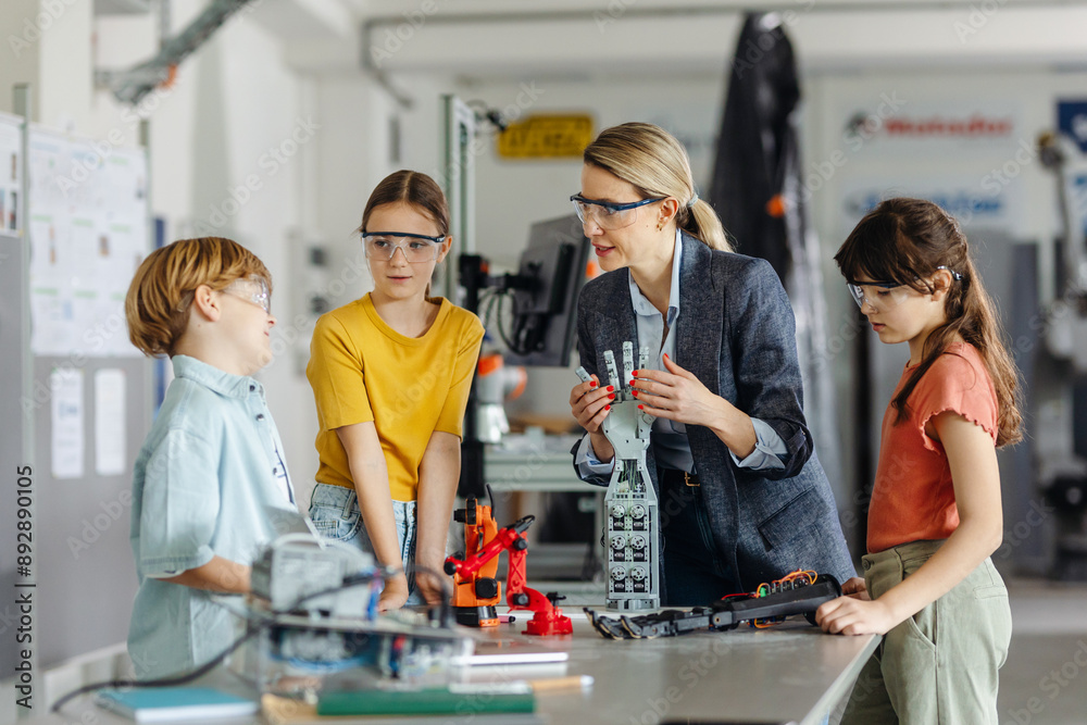Children learning robotics in Elementary school. Young students building robot in after school robotics club. Field trip to real robotics laboratory.