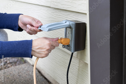 Plugging extension cord into an outdoor outlet. Outdoor electrical outlet