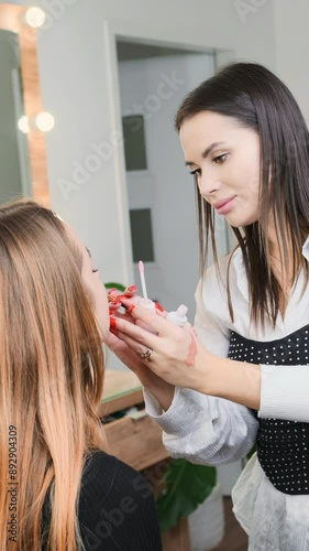 A makeup artist is applying lipstick to a woman in a beauty salon