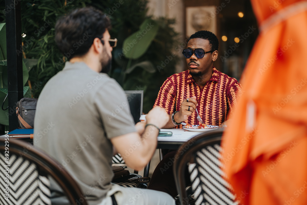 Two businesspeople engaged in a conversation at an outdoor cafe, featuring laptops and notepads on the table. Professional setting with a casual atmosphere. Two businesspeople engaged in a conversation at an outdoor cafe, featuring laptops and notepads on the table. Professional setting with a casual atmosphere.