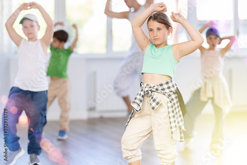 Portrait of confident tween girl hip hop dancer training during group dance class in modern dance studio