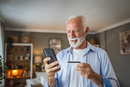 senior man buy online on mobile phone and use credit card at home