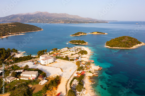 Picturesque drone view of famous Albanian resort of Ksamil on coast of Ionian sea with sandy beaches and turquoise water on sunny spring day photo