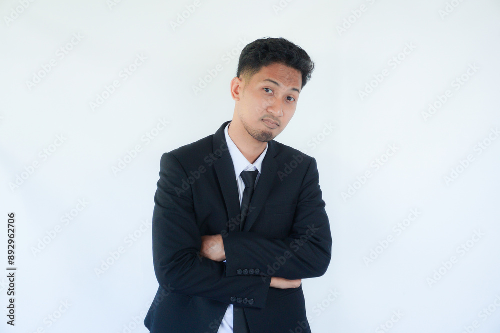 Adult Asian man wearing black suit and tie showing fierce face with his hands on hip Adult Asian man wearing black suit and tie showing fierce face with his hands on hip